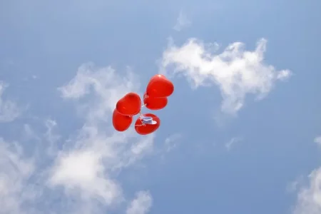 Was bedeutet Loslassen? Zu sehen sind fliegende Luftballons in Herzform